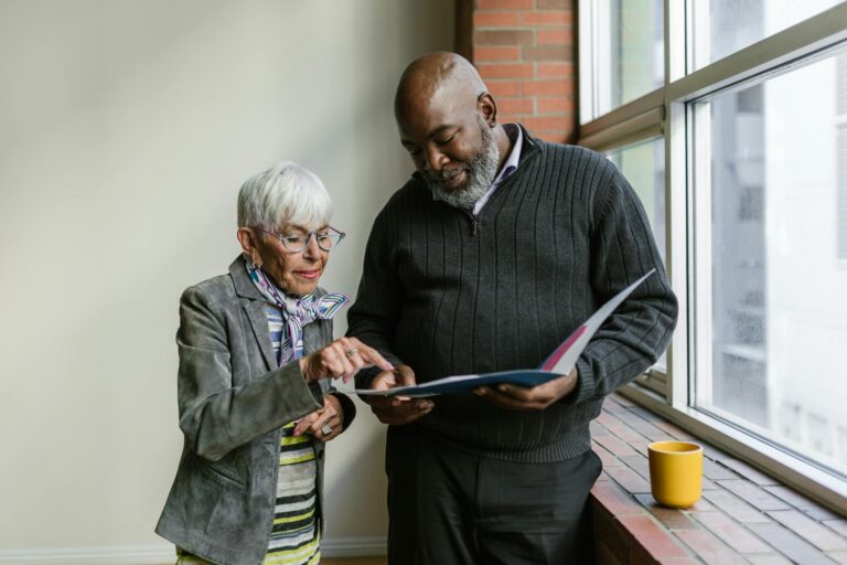an elderly man and woman having conversation while looking at the folder