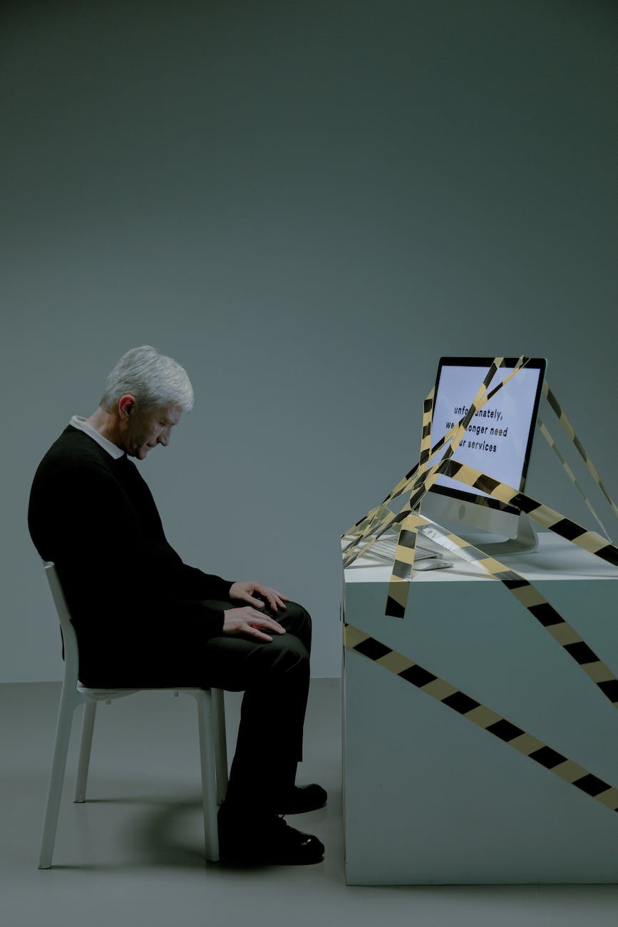 elderly man sitting at a desk with a computer wrapped with a tape