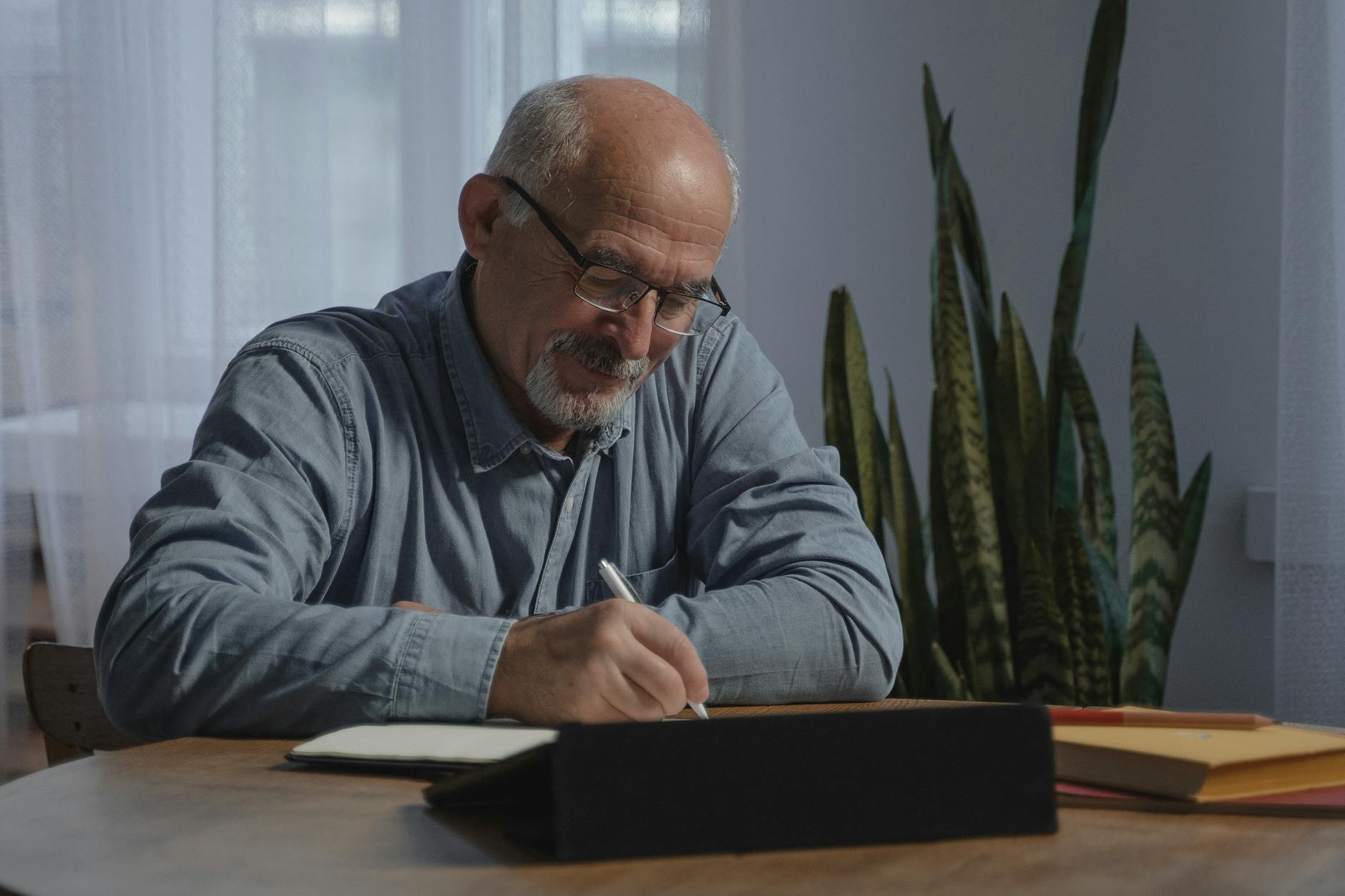 man wearing a gray long sleeve shirt writing on a notebook